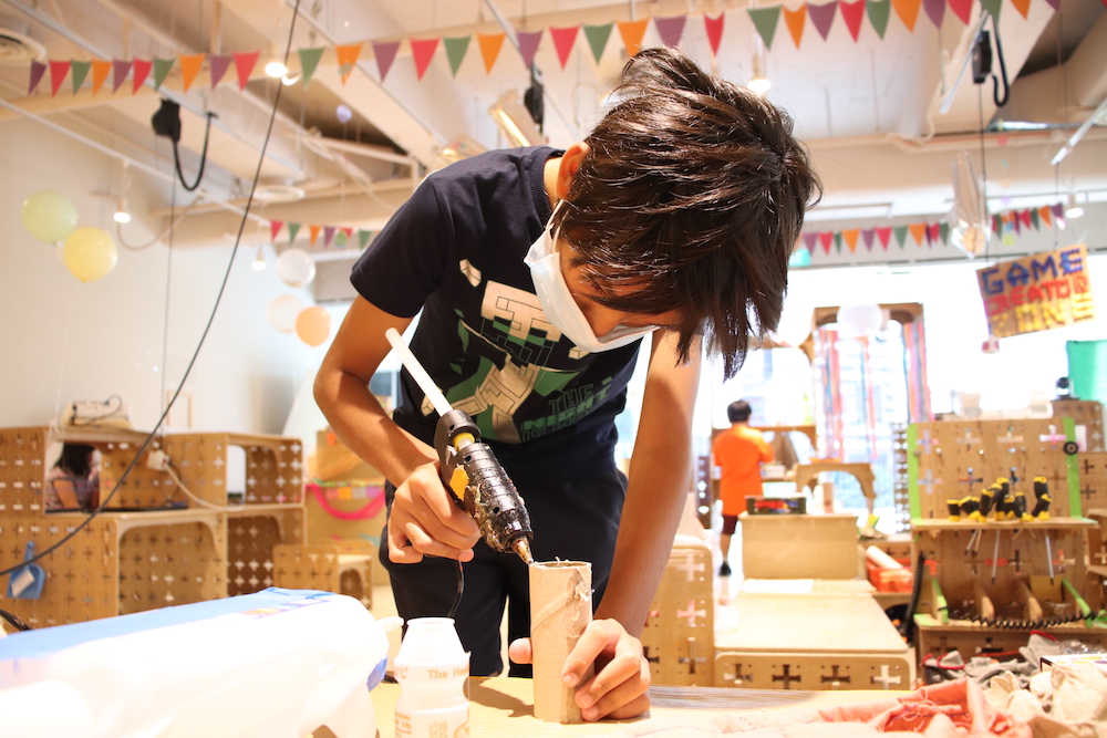 Kid using a glue gun and building prototyoe